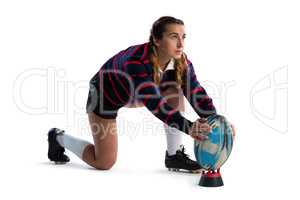 Full length of young female athlete keeping rugby ball on tee