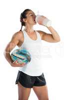Female rugby player holding ball while drinking energy drink