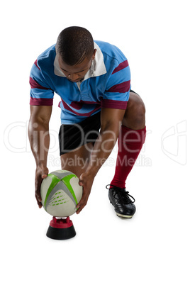 Full length of male rugby player keeping ball on tee