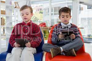 Kids as business executives using digital tablet while sitting