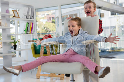 Boy as business executives pushing his colleague on chair