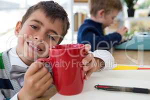 Boy as business executive holding coffee mug in office
