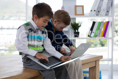 Kids as business executives using laptop while sitting on table