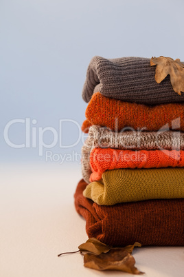 Stack of woolen clothing with autumn leaves