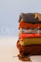 Stack of woolen clothing with autumn leaves