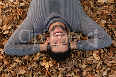 Overhead of man lying on autumn leaves