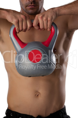 Midsection of shirtless sports player exercising with kettle bell