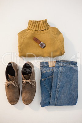 Pair of shoes, sweater, jeans and watch on white background