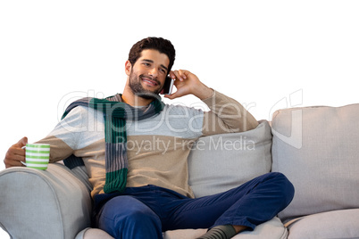 Man talking on mobile phone while having coffee against white background