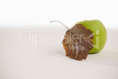 Close-up of green apple and autumn leaves