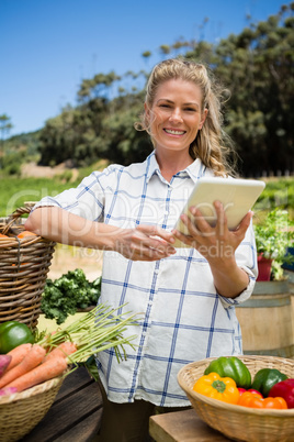 Happy woman using digital tablet at vegetable stall
