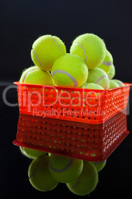 Close up of tennis balls in red plastic basket with reflection