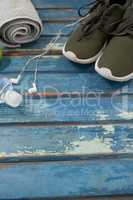High angle view of sports shoes and napkin by headphones with bottle on table