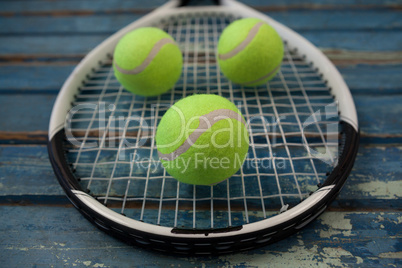 Close up of fluorescent yellow tennis balls on racket over table