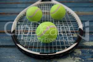 Close up of fluorescent yellow tennis balls on racket over table