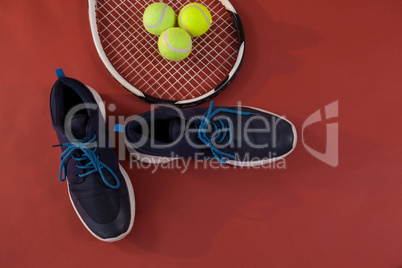 Overhead view of blue sports shoes by tennis racket and balls