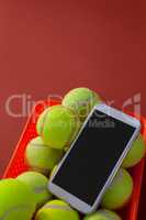 High angle view of smartphone and tennis balls in basket