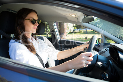 Senior woman looking into rear view mirror while driving a car