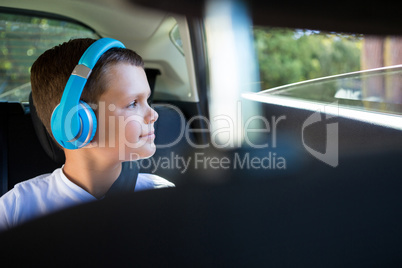 Teenage boy with headphones sitting in the back seat of car