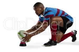 Side view of male rugby player keeping ball tee