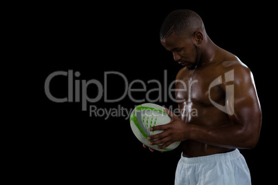 Shirtless male athlete holding rugby ball