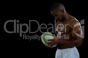 Shirtless male athlete holding rugby ball