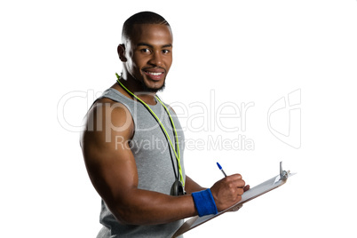 Portrait of smiling male rugby coach writing on clipboard