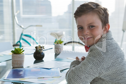 Boy as business executive smiling while sitting in office