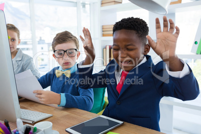 Boy as business executive laughing while looking at digital tablet