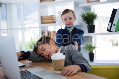 Boy as business executive sleeping while holding coffee cup