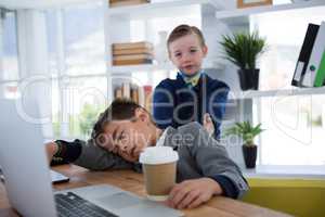 Boy as business executive sleeping while holding coffee cup