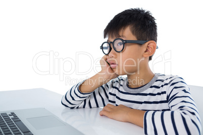 Boy sitting with laptop against white background