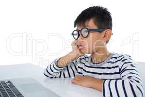 Boy sitting with laptop against white background