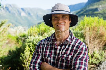 Portrait of smiling farmer standing with arms crossed