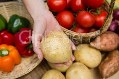 Woman holding fresh potato at vegetable stall