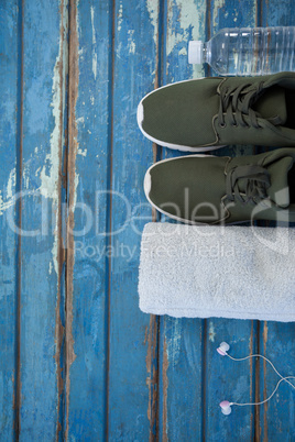 Overhead view of sports shoes and napkin by headphones with water bottle