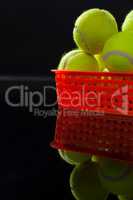 Close up of fluorescent yellow tennis balls in plastic basket with reflection