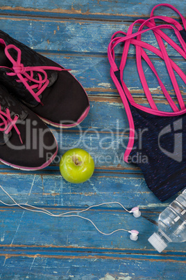 Overhead view of womenswear with Granny Smith apple and bottle by headphones