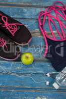 Overhead view of womenswear with Granny Smith apple and bottle by headphones