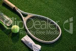 High angle view of tennis ball with racket and napkin by water bottle