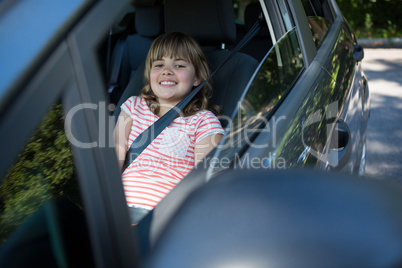 Teenage girl sitting in the back seat of car