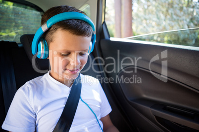 Teenage boy with headphones sitting in the back seat of car