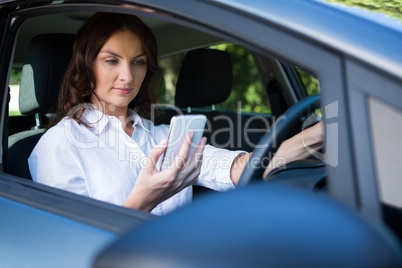 Woman using mobile phone while driving a car