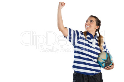 Happy female athlete holding rugby ball while standing with clenching fist