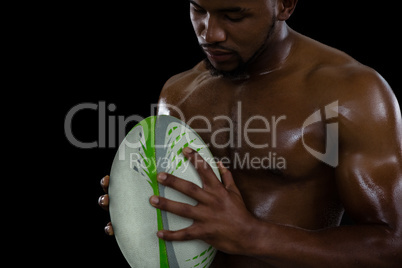 Shirtless male rugby player holding ball