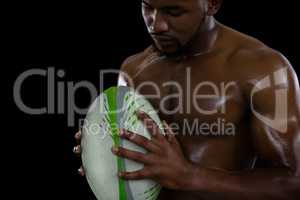 Shirtless male rugby player holding ball