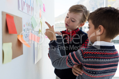 Kids as business executives discussing over bulletin board