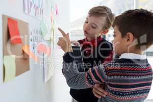 Kids as business executives discussing over bulletin board