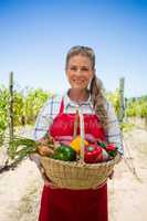 Portrait of happy woman holding a basket of fresh vegetables