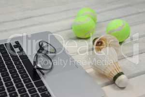 High angle view of eyeglasses on laptop by shuttlecocks and tennis balls